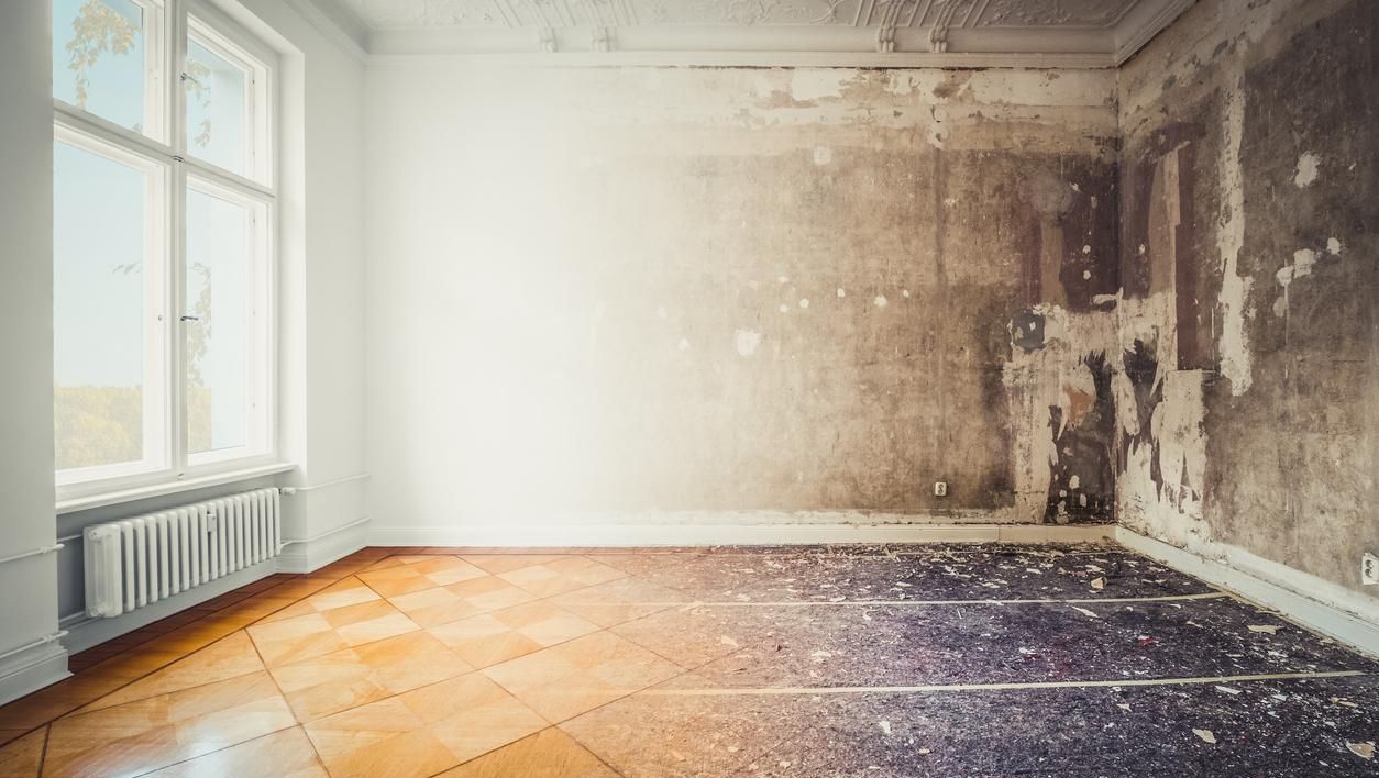 Et rom i en bolig der halvparten er ferdig oppusset og resten har slitt gulv og ubehandlede vegger.