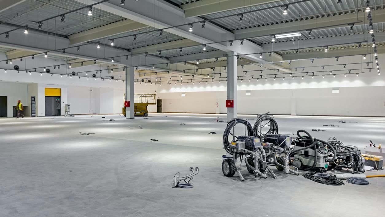 Et stort industrilokale under oppussing med verktøy, ledninger og belysning montert i taket.